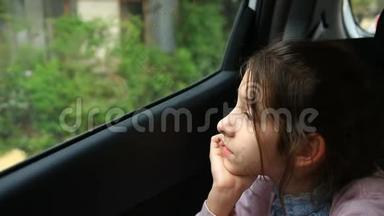 无聊的小女孩坐在车里，透过窗户凝视着太空-路过的树木的巨大倒影